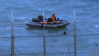 Moroccan soldiers remove a migrant from the water near Ceuta's border fence