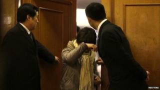 A family member of a passenger shields herself from journalists as she exits a rest area for relatives of passengers of Malaysia Airlines flight MH370, after a morning meeting at Lido Hotel in Beijing, 12 March 2014