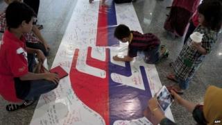 Visitors write on a banner carrying messages for the passengers of missing Malaysia Airlines flight MH370 at Kuala Lumpur International Airport (KLIA) in Sepang, outside Kuala Lumpur on 16 March 2014