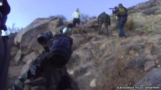 Police officers point their guns at a camper