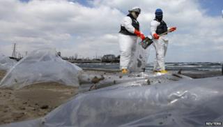 Men in suits cleaning up oil from beach