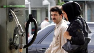 Iranian couple walks past a petrol station in Tehran (archive)