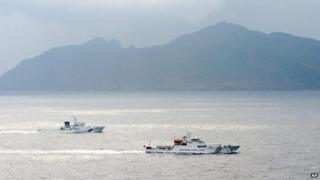 In this 23 April 2013 file photo, a Japan Coast Guard vessel (L) sails along with a Chinese surveillance ship near the disputed islands