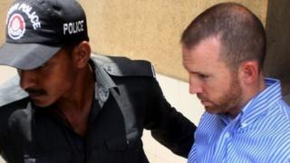 In this photograph taken on May 6, 2014 Pakistani policemen escort an alleged US FBI agent under arrest as they leave the local court in Karachi.