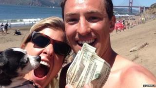 Man, woman and dog on beach holding some cash