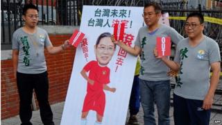 Supporters from the opposition Taiwan Solidarity Union display red cards next to an image of Zhang Zhijun, director of China's Taiwan Affairs Office, outside the parliament during a protest in Taipei on 24 June 2014.