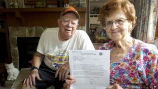 Harold Weaver sits behind his wife, Martha, in their Nickleville, Pennsylvania home. Martha holds a letter from the Selective Service for her late father, Fred Minnick, requiring him to register for the nation's military draft 8 July 2014