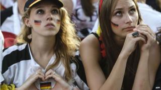 German fan forms a heart with her hands that frames the German national flag during World Cup quarter-final match between Germany and France at the Brandenburg Gate in Berlin, Germany on 4 July 2014