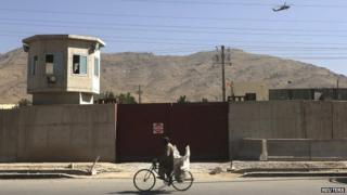 A Nato helicopter flies overhead at the site of the attack outside the counter-narcotics office near Kabul International airport