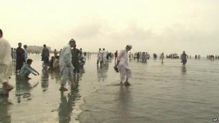 Members of family stand watching rescue operation on Karachi beach on 31 July 2014