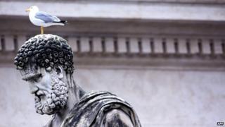 A gull stands on a stained statue of St Peter