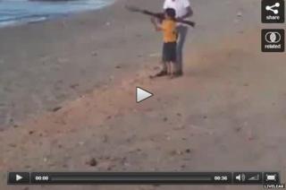 Young boy firing a rocket propelled grenade on a beach