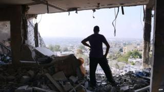 Palestinian man in rubble of apartment complex, Gaza