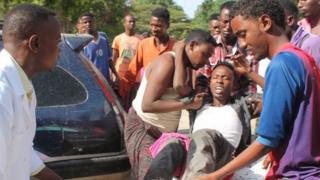 Relatives carry a wounded man who was injured during clashes after government troops launched attacks on a house of a warlord - Mogadishu, Somalia, 15 August 2014