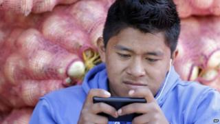 A young man texts at a market in Quito as government prepares to introduce electronic currency