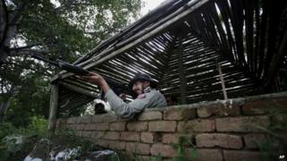 A Pakistani paramilitary soldier stands alert inside a bunker to monitor an area on the border of Pakistan and India in Dhamala Hakimwala, Pakistan, Wednesday, Oct. 8, 2014.
