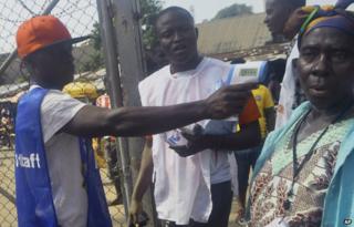 An election workers takes the temperature of a voter in the West Point slum before she casts her vote, during the senate election in Monrovia, Liberia. Saturday, Dec. 20, 2014