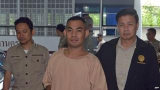 Patiwat Saraiyaem (centre) is escorted by prison officials as he arrives at the criminal court in Bangkok on October 27, 2014