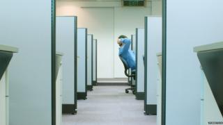 Man leans back in cubicle