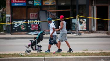 A couple walk in front of burning building