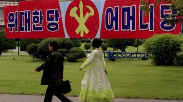 North Koreans walk past a slogan which reads "Great Party, Mother Party" along a sidewalk Wednesday, May 4, 2016, in Pyongyang, North Korea.