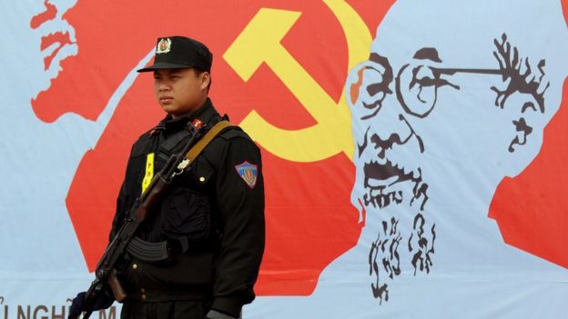 An armed policeman stands guard next to a portrait of late president Ho Chi Minh (R), founder of today's communist Vietnam, and Russian communist leader Vladimir Lenin (L), outside the venue of the current 11th national congress of the Vietnam Communist Party (VCP) in Hanoi on January 17, 2011.