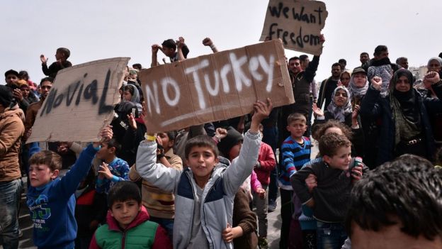 A migrant boy holds up a sign reading 'No Turkey'