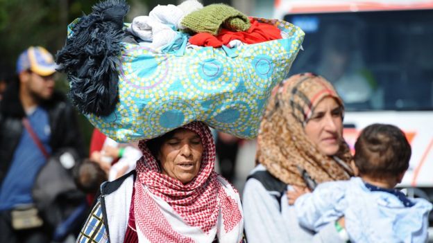 A refugee woman from Syria carries a bag with personal things on top of her head at a tent village for migrants at the Donnersberg bridge close to the central train station in Munich, Germany, 13 September 2015