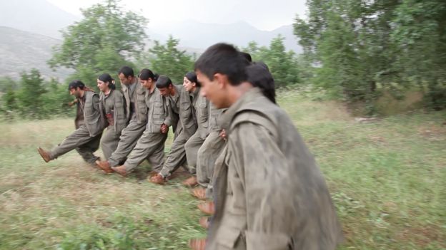 PKK fighters dance after the funeral of four comrades killed by IS