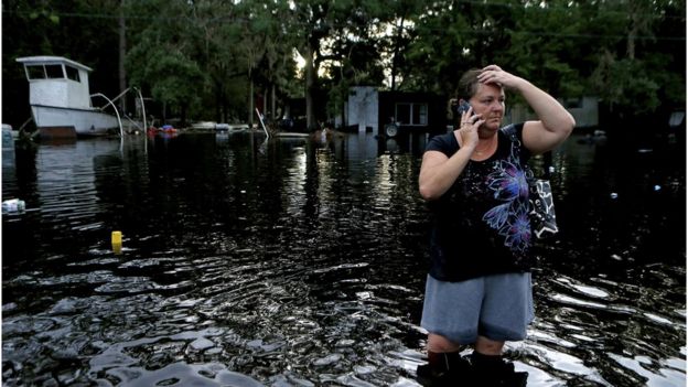 Lynne Garrett speaks to loved ones on the phone as she surveys damage outside of her home from the winds and storm surge associated with Hurricane Hermine which made landfall overnight in the area on 2 September 2016 in Tampa, Florida
