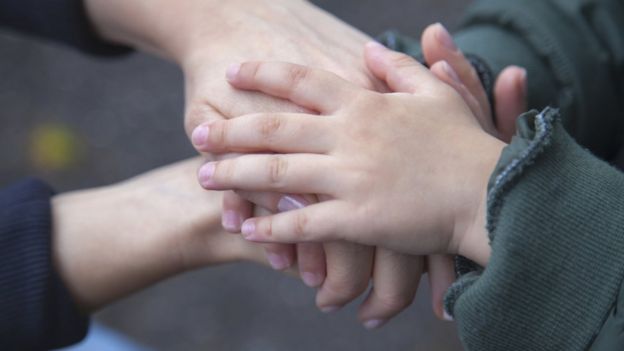 Child and adult hold hands