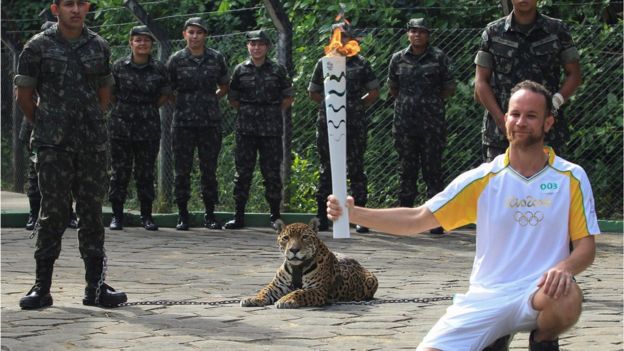 Brazilian physiotherapist Igor Simoes Andrade poses for picture next to jaguar Juma as he takes part in the Olympic Flame torch relay in Manaus, Brazil, 20 June 2016.