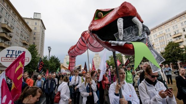Protesters hold a giant snake with dollar notes in its mouth to demonstrate against the TTIP and CETA free trade agreements with a giant puppet on 17 September, 2016 in Berlin, Germany.