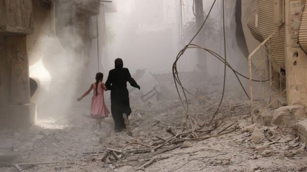 Una mujer corre por las calles demolidas de una ciudad siria.