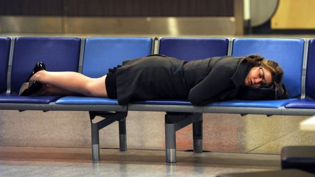 Mujer duerme en un aeropuerto.