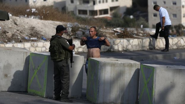 An Israeli border guard inspects a Palestinian man at a newly erected checkpoint at the exit of the east Jerusalem neighbourhood of Issawiya on October 19, 2015