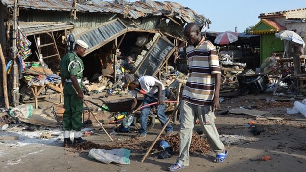 A man walks past a the scene of a bombing after at least 20 people were killed when a young female suicide bomber detonated her explosives at a bus station in Maiduguri, northeast Nigeria, on June 22, 2015 in an attack likely to be blamed on Boko Haram