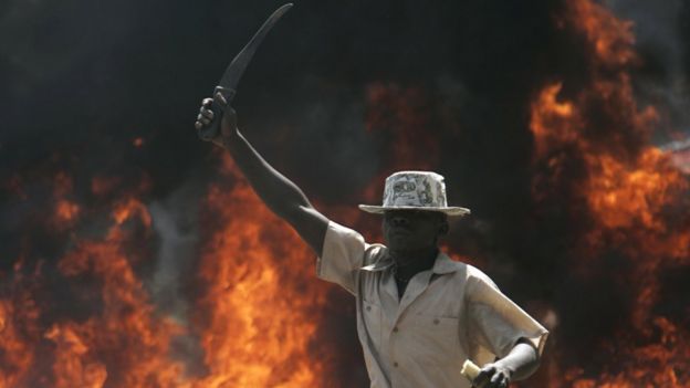 A supporter of the Orange Democratic Party holds up a machete in front of a burning barricade, Saturday, Dec. 29, 2007 during riots in the Kibera slum in Nairobi.