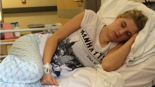 Fotografía de Phoebee recostada en una cama de hospital con mientras le suministran suero.