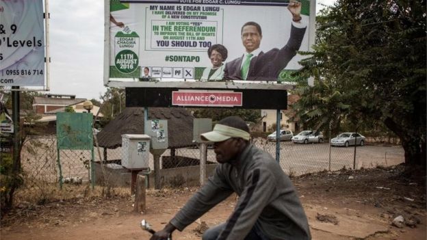 A man rides a bicycle by a presidential campaign billboard of Zambian incumbent president and leader of Zambian ruling party Patriotic Front Edgar Lungu two days ahead of Zambian Presidential and legislative elections on August 8, 2016