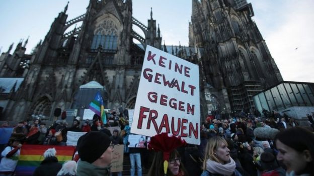 A demonstrator holds a sign in German that reads
