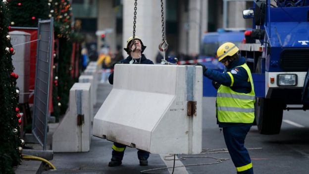 Workers place concrete barriers outside the Christmas market at Breitscheid square in Berlin