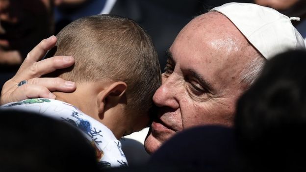 Pope Francis hugs a migrant boy