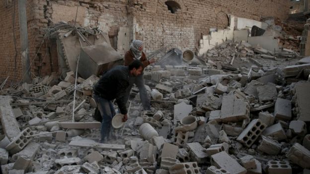 Men search for belongings at a site hit by missiles in the Douma neighbourhood of Damascus, Dec 2015