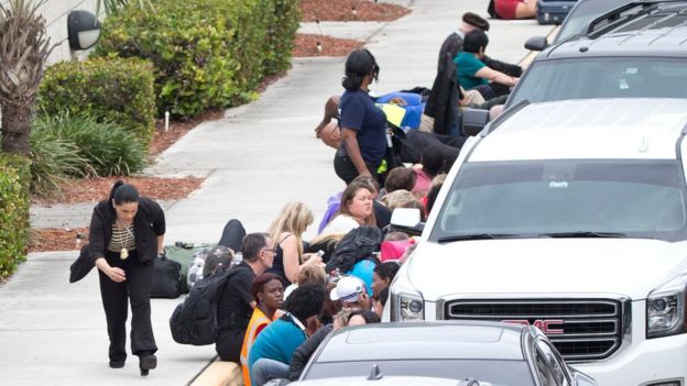 People take cover behind vehicles at Fort Lauderdale's International Airport