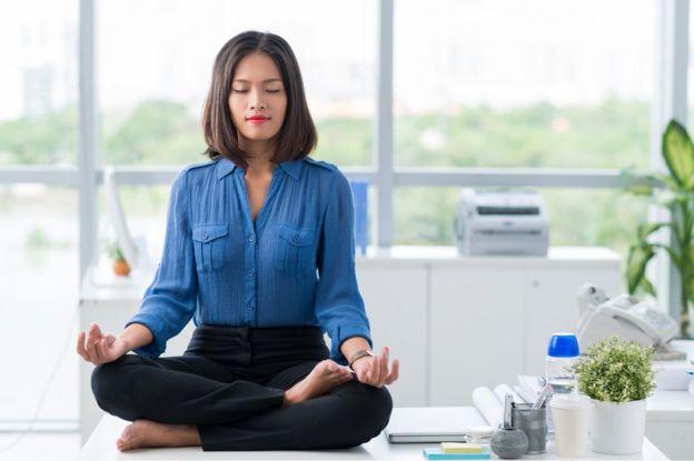 Mulher meditando na mesa de trabalho