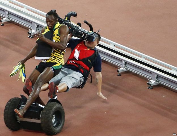 A TV cameraman drives into Usain Bolt of Jamaica after the men