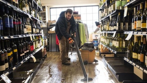 An employee of a liquor store cleans the floor after it flooded following a blizzard on in Stone Harbor, New Jersey (24 January 2016)