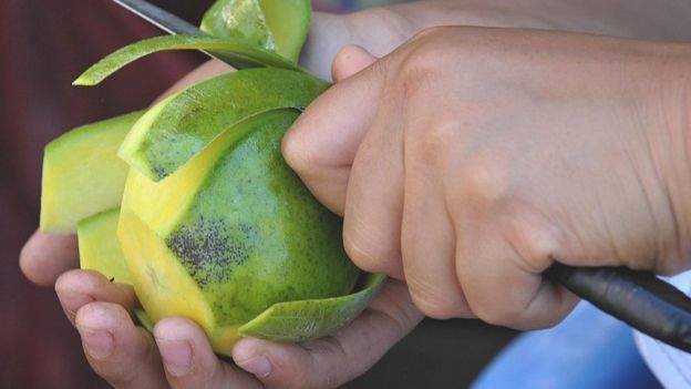 A vendor peels a mango as she sells assorted fruit in the streets of Manila on March 6, 2010.