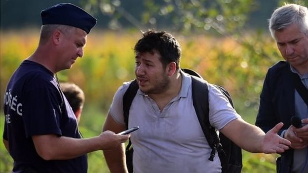 A Hungarian police officer questions a migrant near Roszke. Photo: 14 September 2015